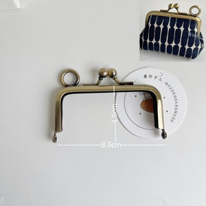 May include: A gold metal purse frame with a 4.5 cm by 8.5 cm opening. The frame is designed to be used for crafting purses and bags.