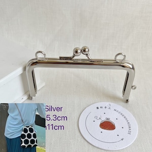 May include: Silver-toned metal purse frame with two round handles and a decorative ball clasp. The frame measures 5.3 inches wide and 11 inches long.