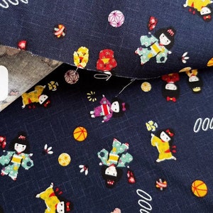 May include: A dark blue fabric with a repeating pattern of small, colorful Japanese dolls wearing traditional clothing. The dolls are surrounded by small, colorful circles and other decorative elements.
