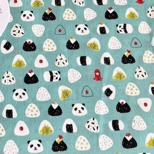 May include: A teal fabric with a repeating pattern of white rice balls, black and white pandas, and red and white chilli peppers. The fabric has the text "MOZHENHANDMADE" in a white circle with a brown illustration of a loaf of bread.