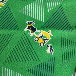 May include: Green fabric with a white and black pattern of rabbits pulling a yellow wagon. The fabric has a white and blue striped pattern. The fabric has a white tag with the text "MOZHENHANDMADE" and "高井土".