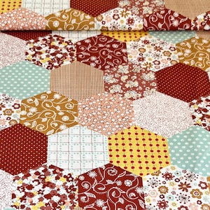 Könnte beinhalten: Ein Stoff mit Patchwork-Muster, das sechseckige Formen in verschiedenen Farben und Mustern zeigt, darunter Rot, Gelb, Braun und Weiß.