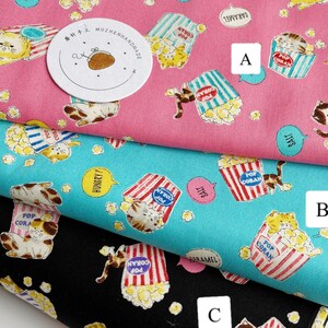 May include: Three fabric swatches with a repeating pattern of cats eating popcorn. The top swatch is pink, the middle swatch is turquoise, and the bottom swatch is black. Each swatch has a different text bubble with a different flavor of popcorn: salt, caramel, and hungry?.