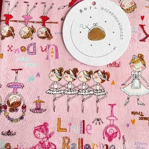 以下が含まれることがあります： バレリーナをテーマにしたピンクと黒の布地3枚。布地には、バレリーナ、バレエシューズ、バレエに関連するテキストが描かれています。テキストには、「リトルバレリーナ」、「キトリラブ」、「アン・ドゥ・トロワ」、「レッスンのリサイタル」が含まれています。