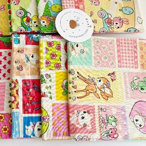Könnte beinhalten: Eine Sammlung von 10 Stoffquadraten mit einem Patchwork-Design in verschiedenen Mustern und Farben. Die Muster umfassen rosa und braunes Gingham, rosa Herzen und einen gelben Hintergrund mit einem sich wiederholenden Muster aus Hirschen, Hasen und Blumen.