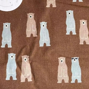 Peut inclure: Tissu brun avec un motif répété d'ours bleu clair, rose et brun. Les ours sont debout et certains portent des lunettes de soleil. Le tissu a une étiquette blanche avec du texte japonais et les mots "Modern Handmade".
