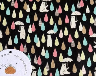 May include: Black fabric with a repeating pattern of white bears holding umbrellas and colorful raindrops. The fabric has a label that says "MOZHENHANDMADE" and "85".