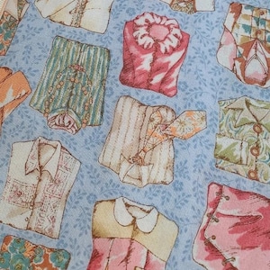 May include: A blue fabric with a repeating pattern of colorful shirts. The fabric is printed with the text "2018 COLLECTION printed by YUWA MADE IN JAPAN".