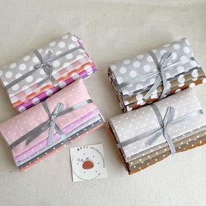 May include: Four stacks of fabric squares with white polka dots on a grey background. The fabric is tied with a grey ribbon. The stacks are arranged in a square shape on a white surface. A small tag with the text "MOZHENHANDMADE" is in the lower right corner of the image.