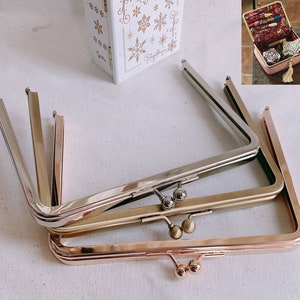 May include: Three different metal purse frames, one silver, one gold, and one rose gold. The frames are stacked on top of each other.
