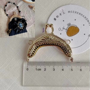 Peut inclure: Cadre de sac à main en métal doré avec un motif décoratif. Le cadre mesure environ 5 cm de long. Le cadre est présenté à côté d'une règle pour référence de taille.