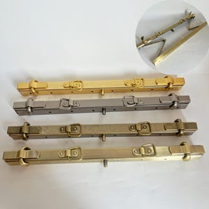 May include: Four metal purse frames in different finishes: gold, silver, antique brass, and brass. Each frame has two clasps and a center pin.