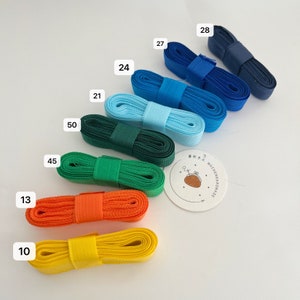 May include: Assortment of colorful ribbon rolls in various widths, labeled with numbers. The ribbon rolls are arranged in a rainbow pattern from yellow to blue. The ribbon rolls are made of a soft, flexible material and have a smooth, satin-like finish.