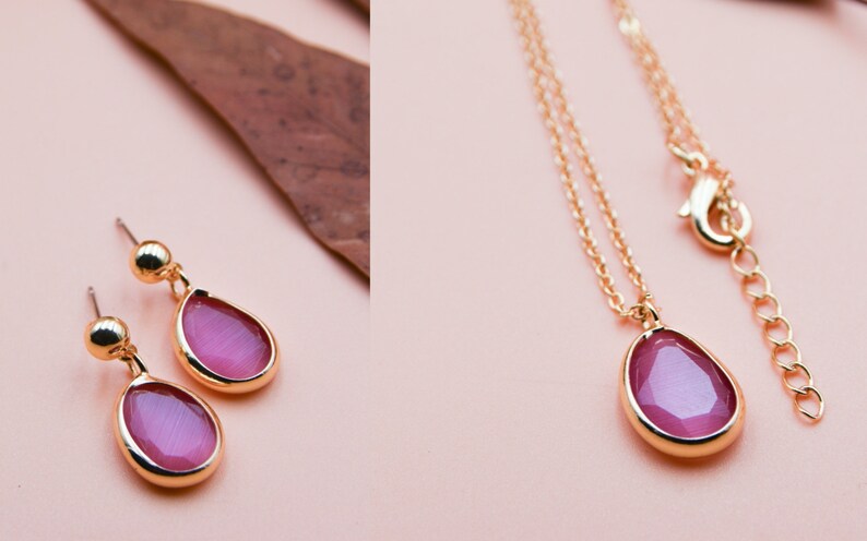 May include: A gold necklace and earrings set with pink teardrop-shaped stones. The necklace has a delicate chain and a lobster clasp closure.