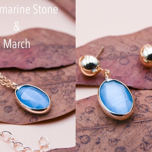 May include: A gold necklace and earrings set with oval-shaped aquamarine stones. The stones are a light blue color and are set in gold.