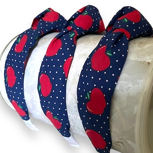 May include: Three navy blue headbands with white polka dots and red apple designs.