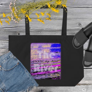Op de afbeelding: Zwarte tote bag met een kleurrijk abstract ontwerp. Het ontwerp toont de woorden "The River floats my boat" in wit en roze. De tas is gemaakt van een duurzaam materiaal en heeft twee zwarte handvatten.