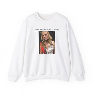 May include: White sweatshirt with a graphic print of a person wearing a crown and holding a cigarette. The text "Make America Great Again" is printed above the graphic.