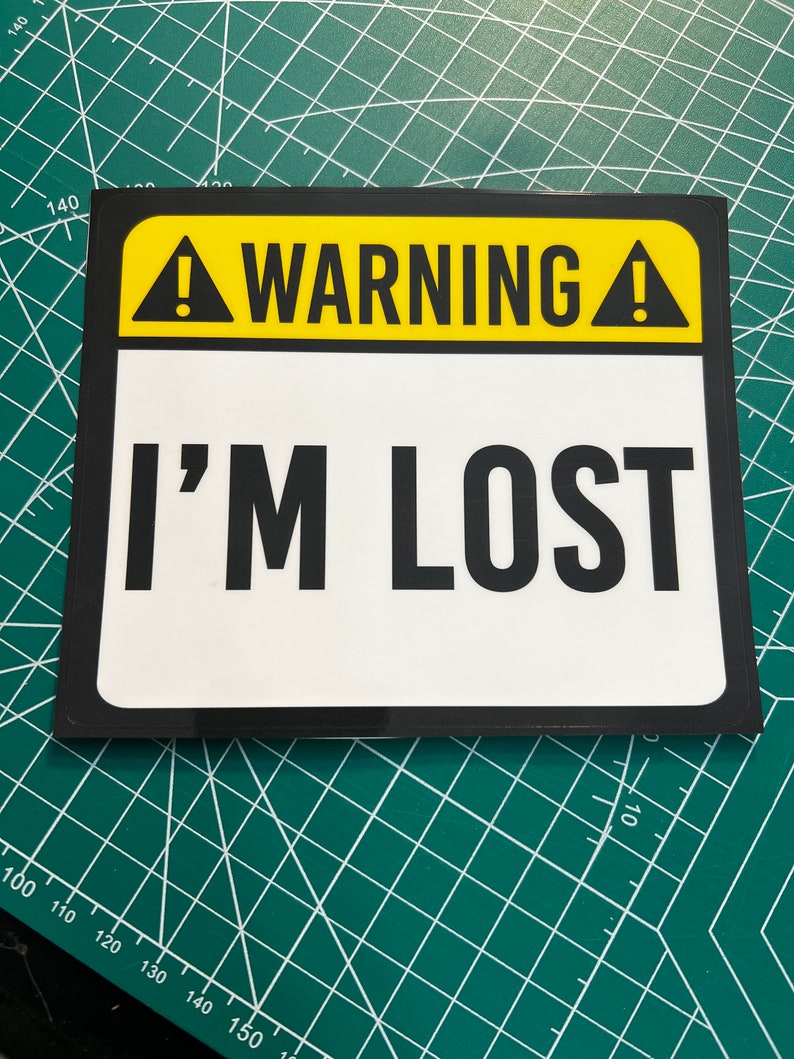 May include: A yellow and black warning sign with an exclamation point and the text "WARNING! I'M LOST" in black.