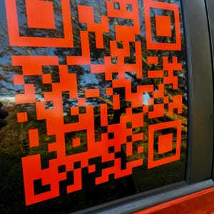 Op de afbeelding: Een feloranje QR-code sticker op een autoruit.