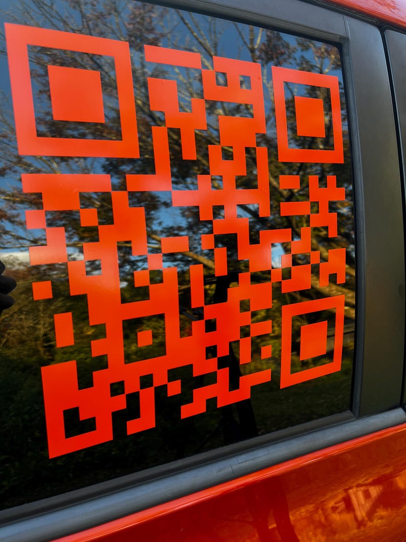 Op de afbeelding: Een feloranje QR-code sticker op een autoruit.