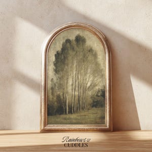 Peut inclure: Une impression d'art murale arqu&eacute;e repr&eacute;sentant un paysage aux tons s&eacute;pia et sourds avec de grands arbres &eacute;lanc&eacute;s dans un champ. L'&oelig;uvre est encadr&eacute;e dans un cadre m&eacute;tallique dor&eacute; patin&eacute; &agrave; sommet arrondi. Le texte "Rainbows & CUDDLES" est visible.