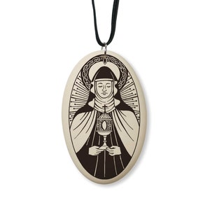 May include: A white oval pendant with a black and white image of a woman in a nun's habit holding a chalice. The pendant is on a black cord.