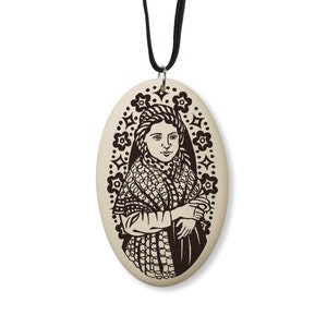 May include: A white oval pendant with a black and white image of a woman wearing a shawl. The pendant is on a black cord.