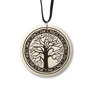 May include: A round, cream-colored pendant with a black Celtic knot design surrounding a dark brown silhouette of a tree. The pendant is attached to a black cord.