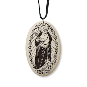 May include: A white oval pendant with a black and white image of Saint John the Evangelist. The pendant is on a black cord.
