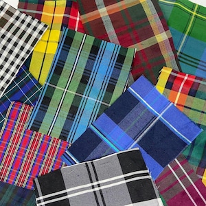 May include: Assortment of plaid fabric swatches in various colours, including red, blue, green, yellow, and black. The fabrics are arranged in a random pattern, overlapping each other.