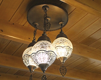 Könnte beinhalten: Ein Kronleuchter mit vier klaren Glaskugeln mit filigranen Metallarbeiten hängt von einer Holzklappen.