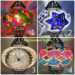 Puede incluir: Cuatro l&aacute;mparas de vidrio mosaico con diferentes dise&ntilde;os. Las l&aacute;mparas est&aacute;n todas sobre un soporte negro con una base redonda. Los dise&ntilde;os son: un mosaico colorido, una estrella azul, un mosaico blanco y un mosaico rosa y azul.