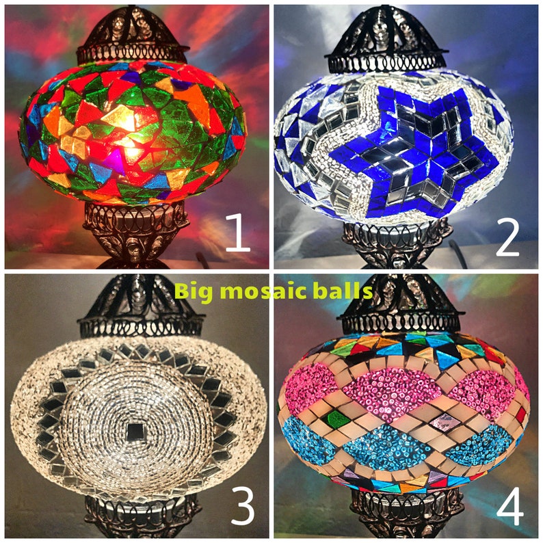 Puede incluir: Cuatro l&aacute;mparas de vidrio mosaico con diferentes dise&ntilde;os. Las l&aacute;mparas est&aacute;n todas sobre un soporte negro con una base redonda. Los dise&ntilde;os son: un mosaico colorido, una estrella azul, un mosaico blanco y un mosaico rosa y azul.