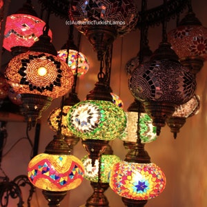 Puede incluir: Una colecci&oacute;n de l&aacute;mparas turcas de estilo mosaico de colores que cuelgan de un techo. Las l&aacute;mparas son redondas y tienen patrones intrincados. Las l&aacute;mparas est&aacute;n encendidas y brillan, proyectando una luz c&aacute;lida.