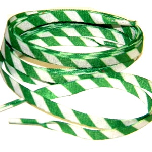May include: Green and white striped shoelaces, diagonally patterned. The laces are a vibrant green and white, with a repeating stripe design. The shoelaces are shown coiled on a white background.