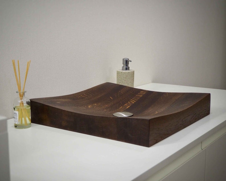 Peut inclure: Un &eacute;vier en bois brun fonc&eacute; avec un design incurv&eacute;. L'&eacute;vier est pos&eacute; sur un comptoir blanc.