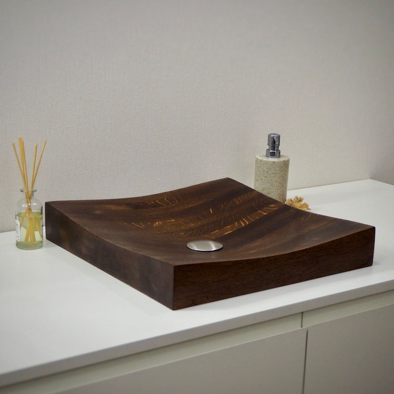 Peut inclure: Un &eacute;vier en bois brun fonc&eacute; avec un design incurv&eacute; et un drain rond en acier inoxydable.