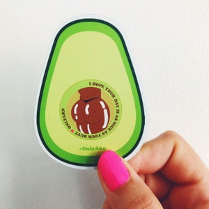 Pode incluir: Adesivo em forma de abacate com borda verde e interior verde claro. O adesivo apresenta uma bunda de desenho animado marrom no centro, rodeada pelo texto "I HOPE YOUR DAY IS AS NICE AS YOUR BUTT" e "OnlyAkn".
