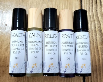 Puede incluir: Cinco botellas de aceite esencial de 10 ml con roll-on y etiquetas. Las etiquetas son blancas con texto negro y presentan diferentes mezclas de aceites esenciales: Salud Apoyo inmunológico, Calma Mezcla de conexión a tierra, Alivio Alivio de la tensión, Descanso Copaiba de lavanda, Renovar Mezcla energizante.