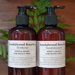 May include: Two brown bottles of shampoo and conditioner with black pump tops. The bottles are labeled "Sandalwood Bourbon" and feature the text "Simple Soaps for Manly Men".