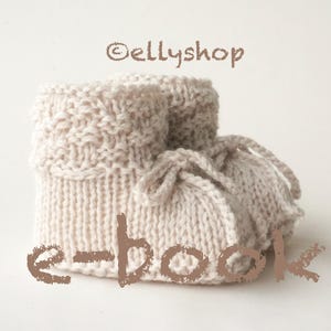 Könnte beinhalten: Ein Paar beige gestrickte Babyschuhe mit umgeschlagenem Bündchen und Schnürverschluss. Der Text "ellyshop" und "e-book" sind auf dem Bild aufgedruckt. Die Schuhe sind aus weichem, strukturiertem Garn.