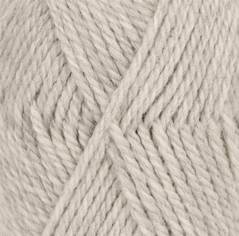 May include: Close-up of a skein of light gray yarn. The yarn has a thick, textured appearance, with visible fibers and a slightly twisted structure. The color is a neutral, soft gray, suitable for various knitting or crochet projects.