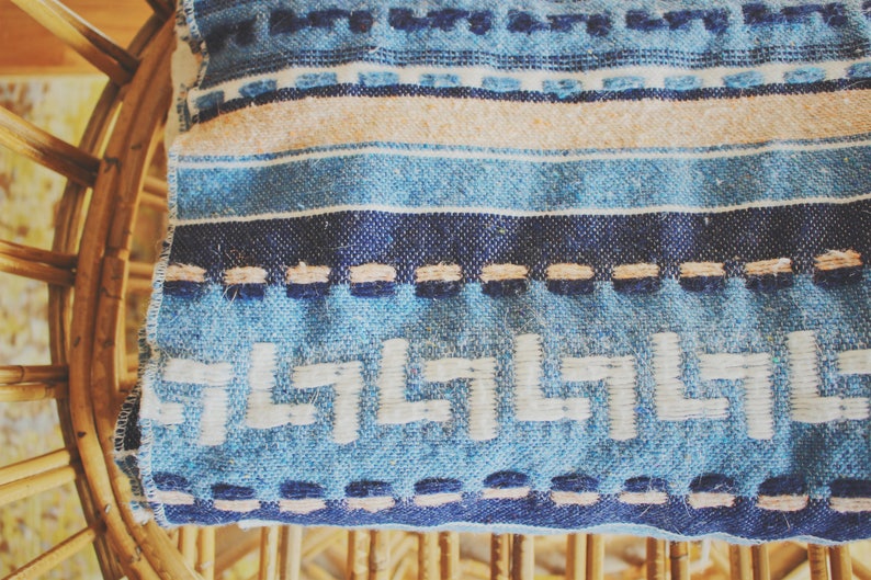 May include: A blue and white striped throw blanket with a geometric pattern. The blanket is woven with a fringe border and has a subtle texture.
