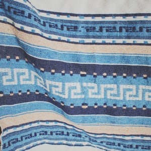 May include: A blue and white woven throw blanket with a geometric pattern. The blanket has a fringe border and is made of a soft, comfortable material.