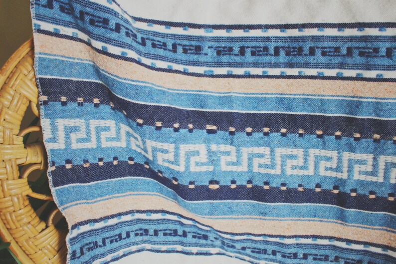 May include: A blue and white woven throw blanket with a geometric pattern. The blanket has a fringe border and is made of a soft, comfortable material.