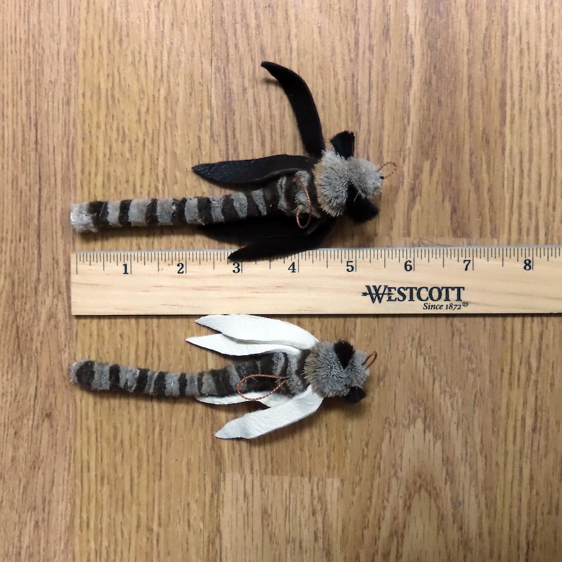 Może przedstawiać: Dwa pluszowe owady ze  striped bodies and wings. Owad na g&oacute;rze ma czarne skrzydła, a owad na dole ma białe skrzydła. Oba owady mają około 13 cm długości i są mierzone przy użyciu drewnianej linijki z tekstem "Westcott Since 1872".