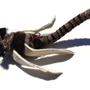 Może przedstawiać: Ręcznie robiona przynęta muchowa z brązowo-białym paskowanym korpusem, białymi skrzydłami i brązową głową z futra.