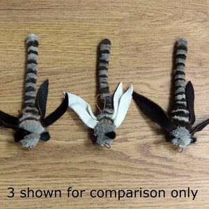 Może przedstawiać: Trzy czarno-białe, prążkowane zabawki dla kota z czarnymi skrzydłami i futrzastą głową. Zabawki pokazane są jedynie w celach por&oacute;wnawczych.