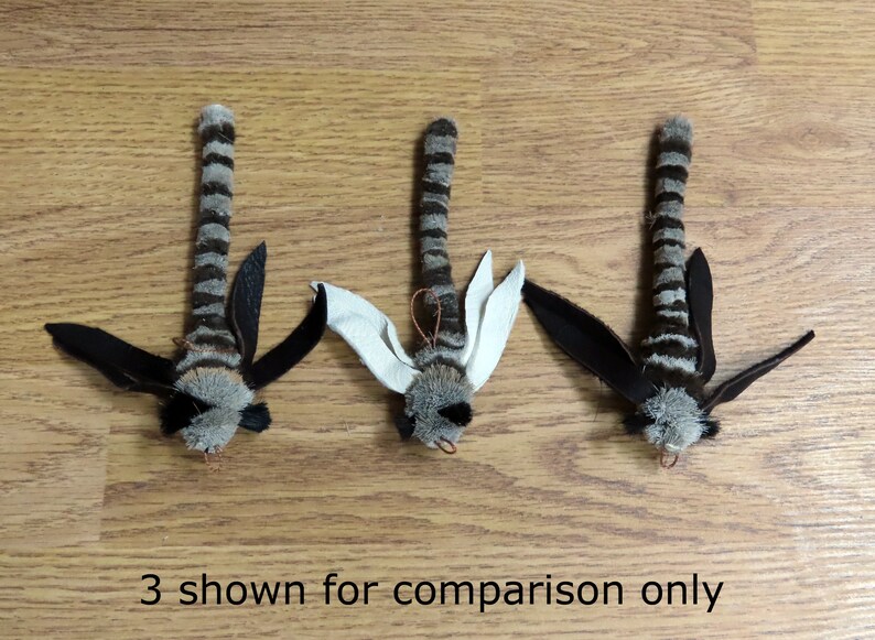 Może przedstawiać: Trzy czarno-białe, prążkowane zabawki dla kota z czarnymi skrzydłami i futrzastą głową. Zabawki pokazane są jedynie w celach por&oacute;wnawczych.